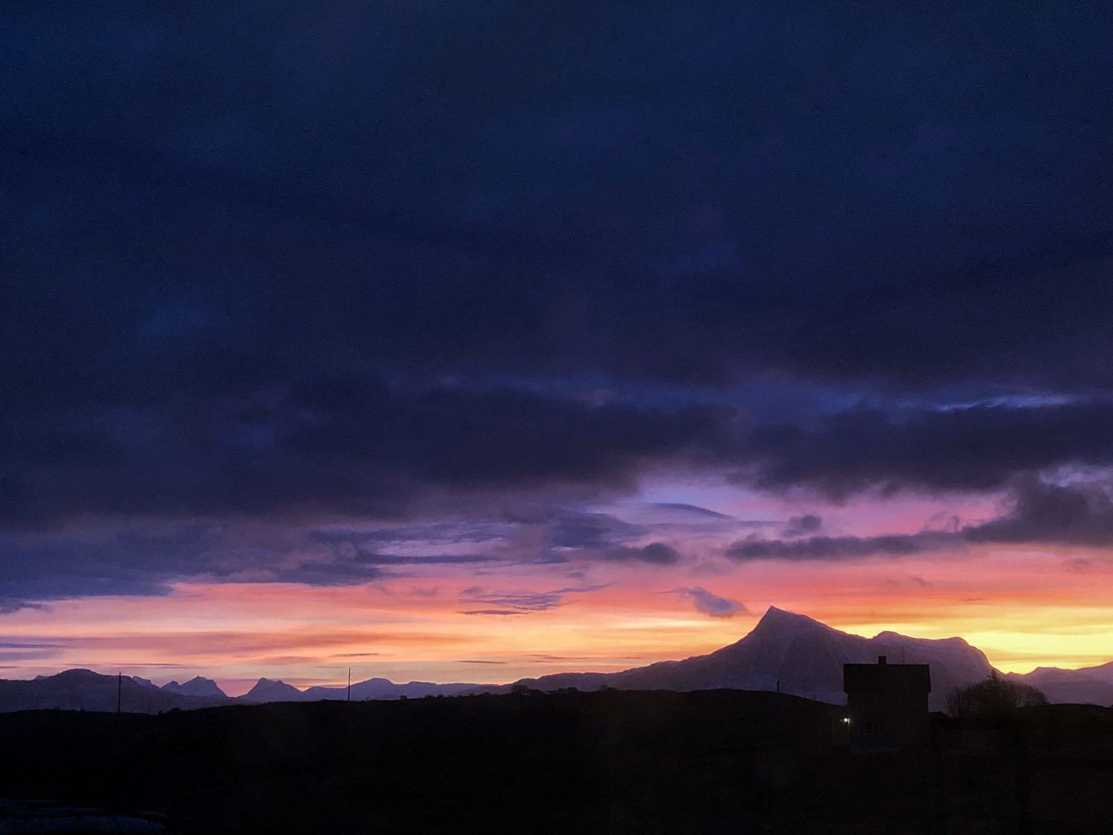 Dusk over the mountains and the sea, the sky turning orange