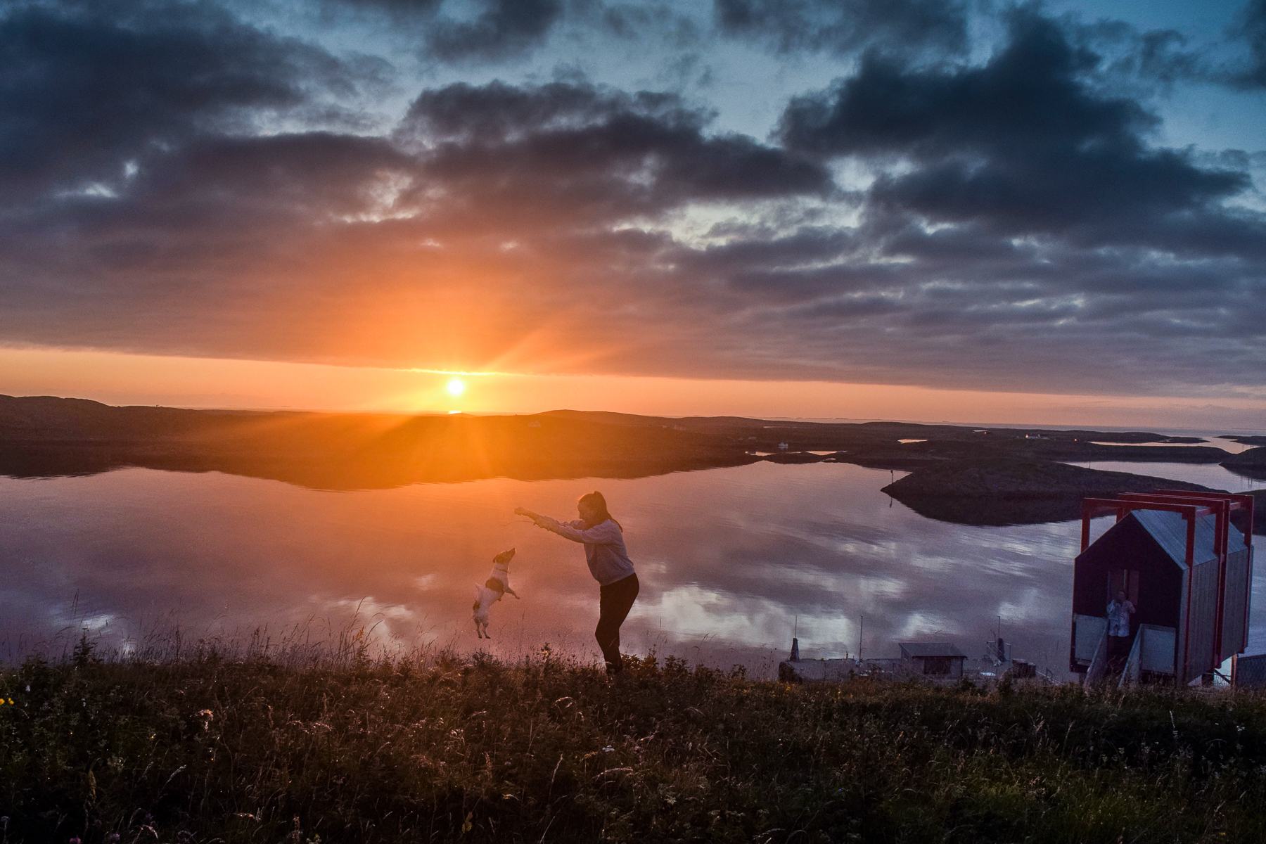 A person on the hill at sunset, looking out over the water