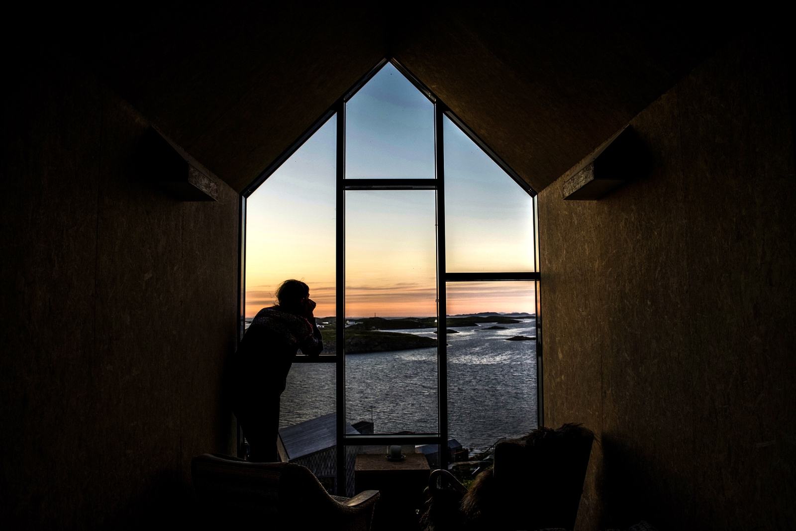 A figure in silhouette in the gable window of the Tower House at sunset