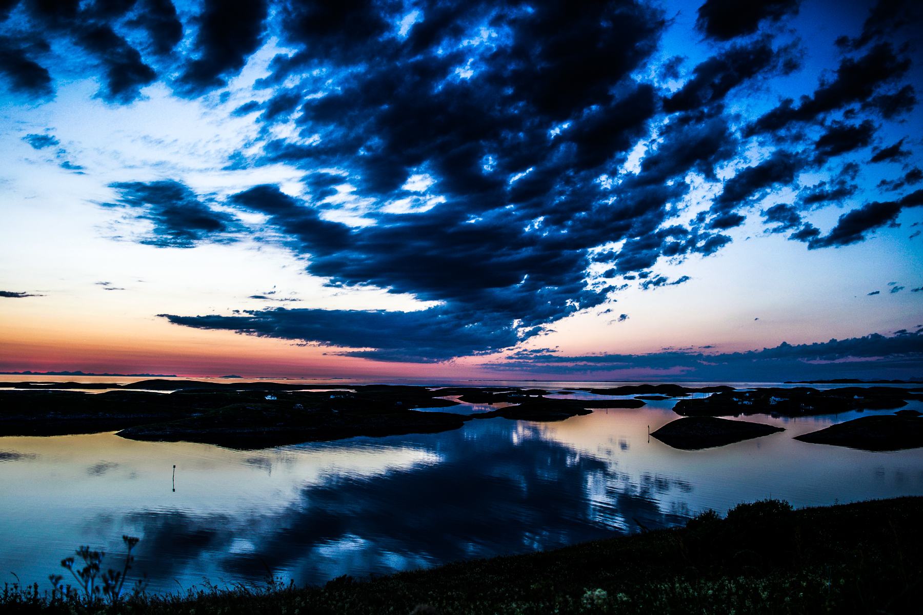 Islands reflected in still water under a blue dusk sky