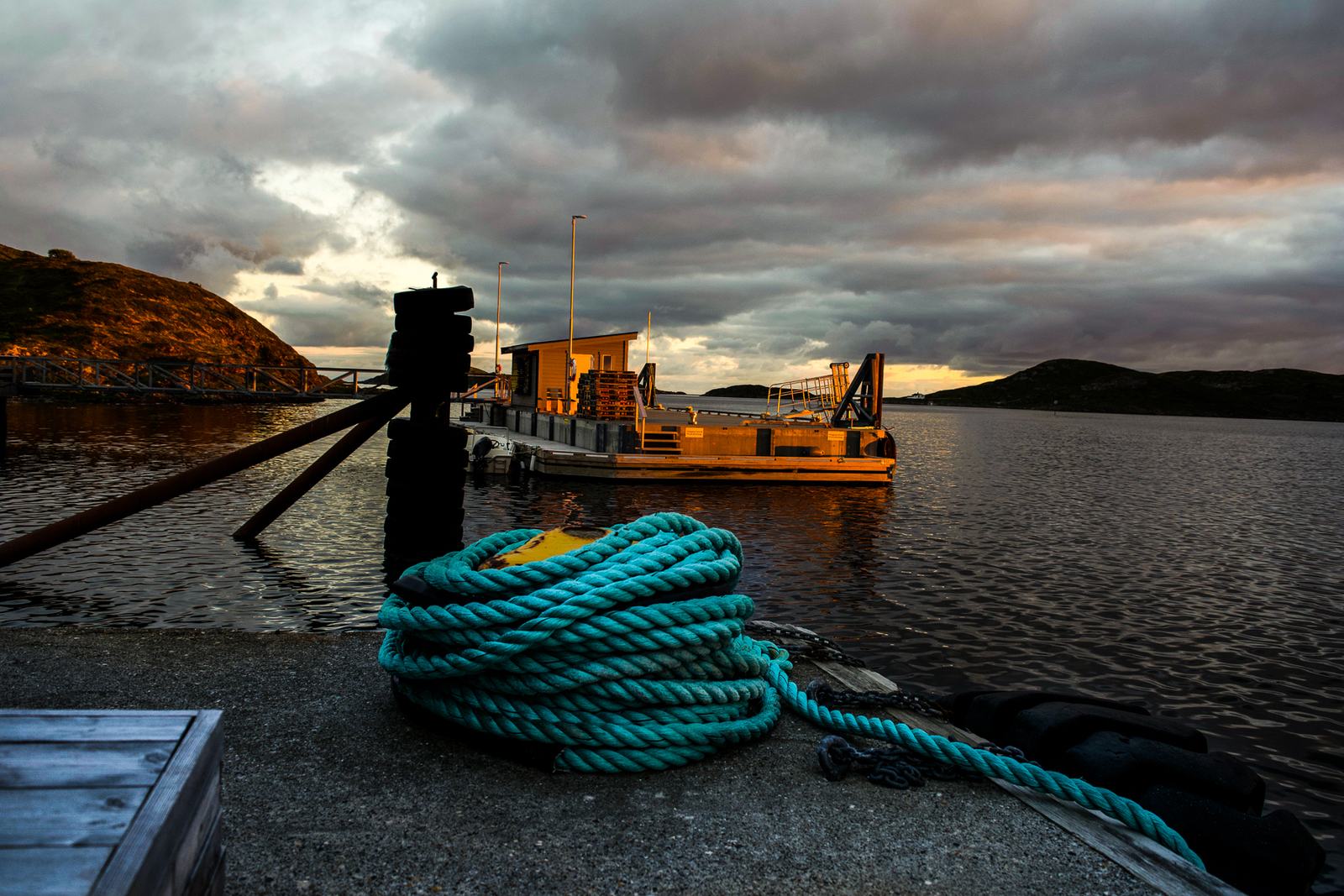 A coil of rope on the quay at sunset, a boat moored behind