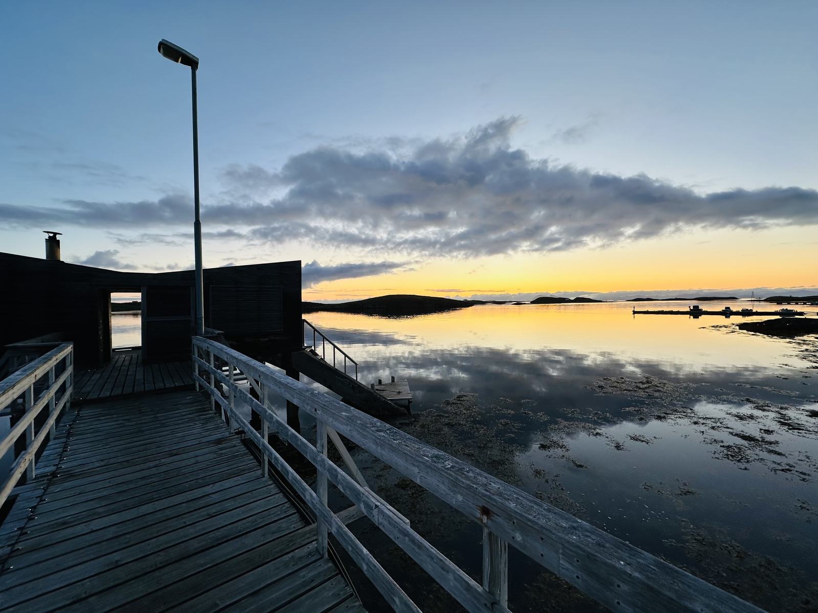 The pier out to the sauna at sunset, the sky reflected in still water