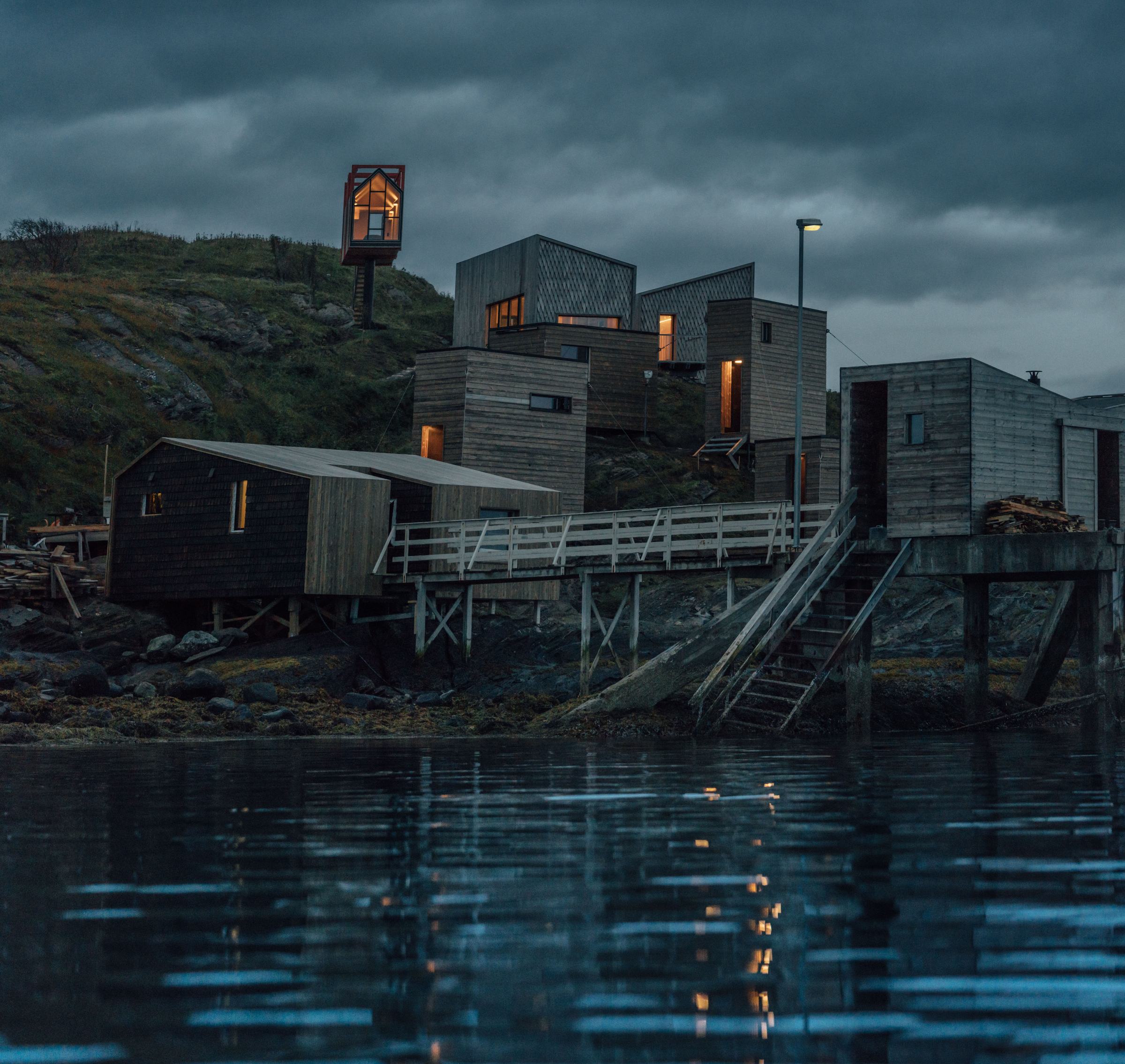 The cabins stacked on the rocks at dusk, reflected in the water