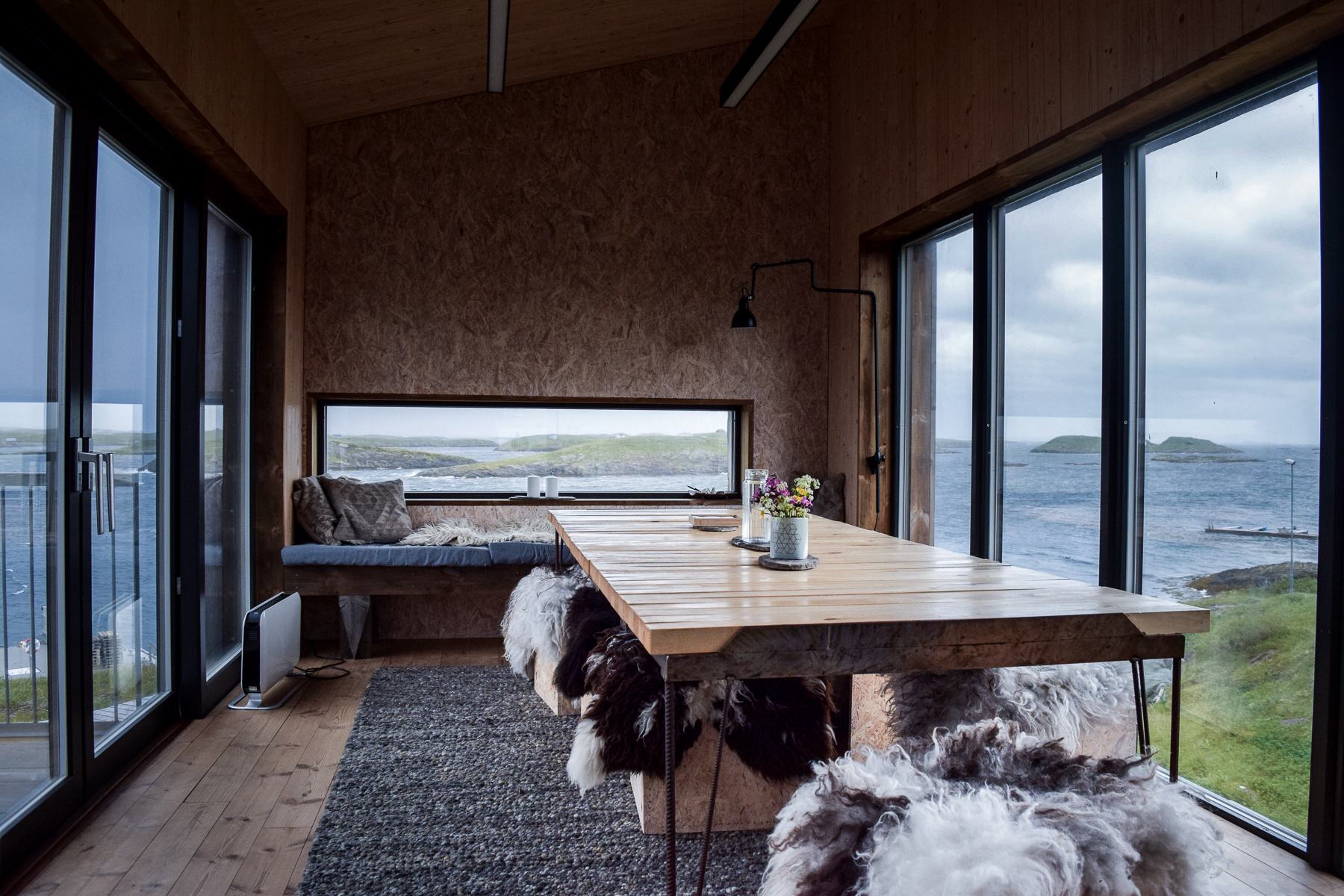 The Kitchen House dining room: long wooden table, sheepskins, windows onto the sea