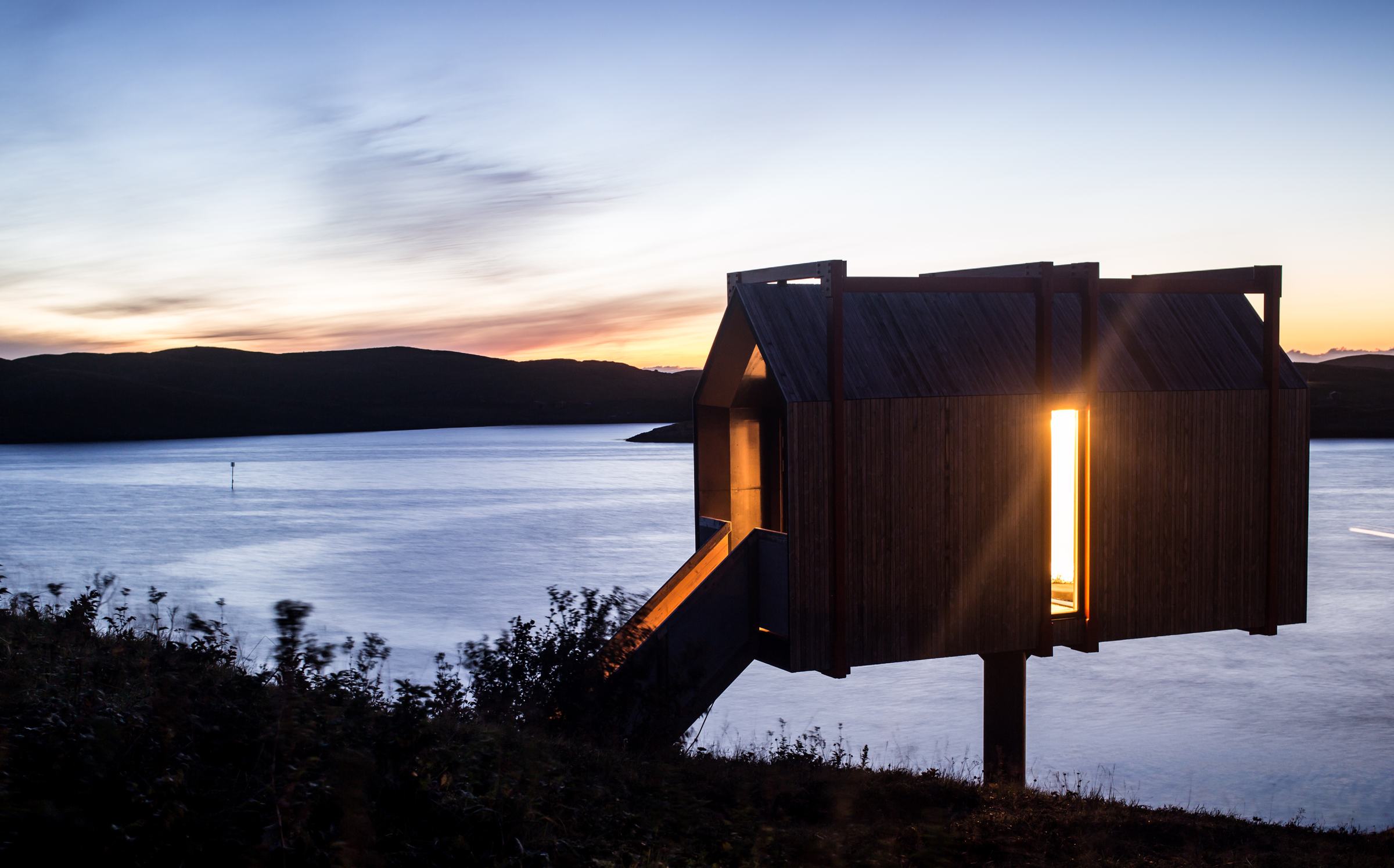 The Tower House in silhouette at sunset, one window lit
