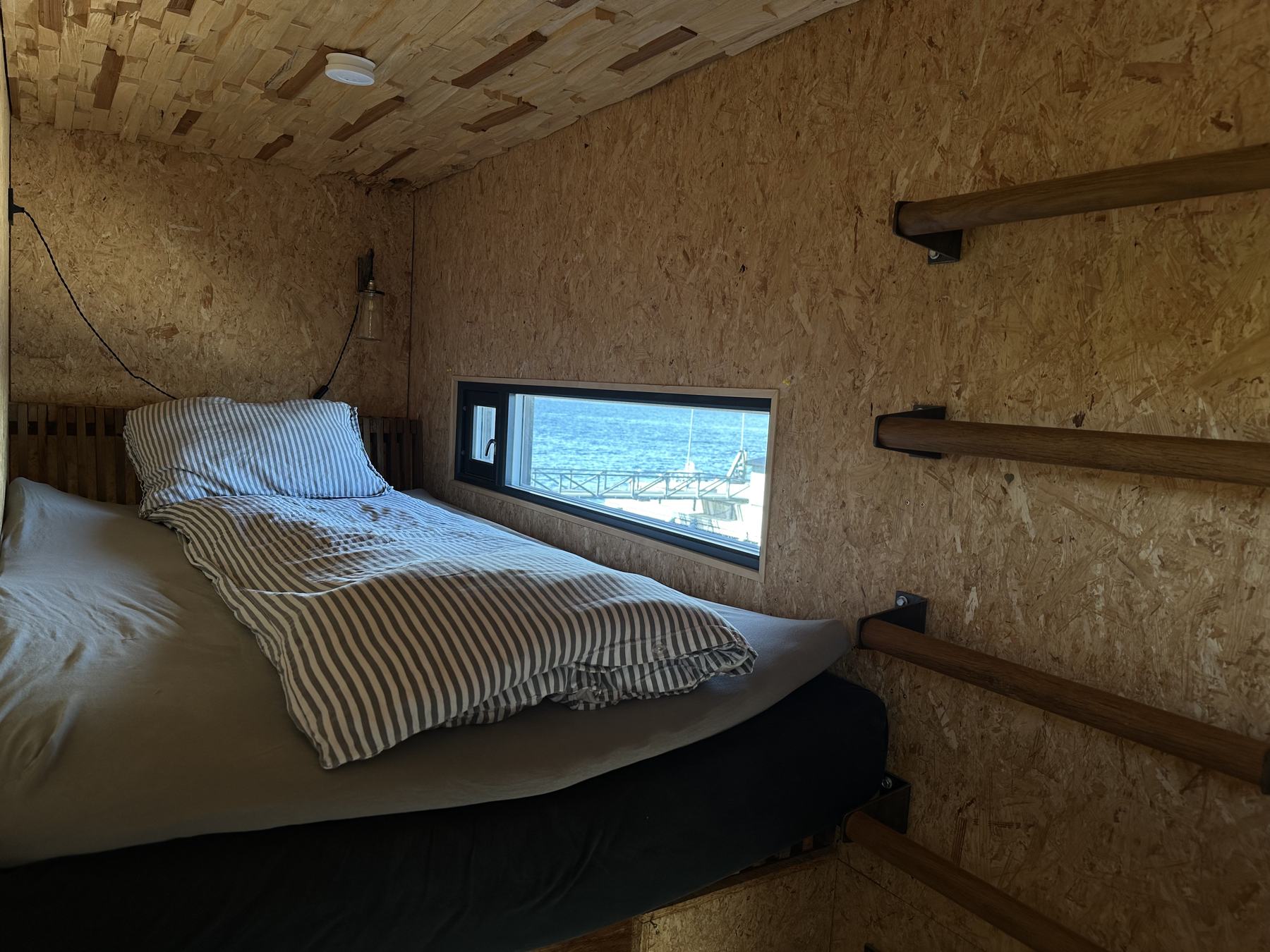 A sleeping cabin: a raised bed under a long window onto the sea