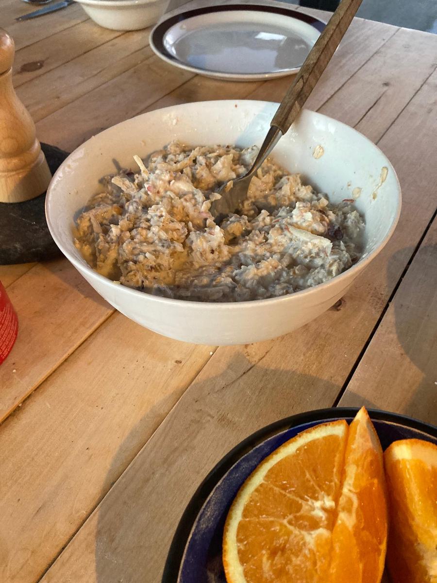 A bowl of porridge and an orange on the wooden table