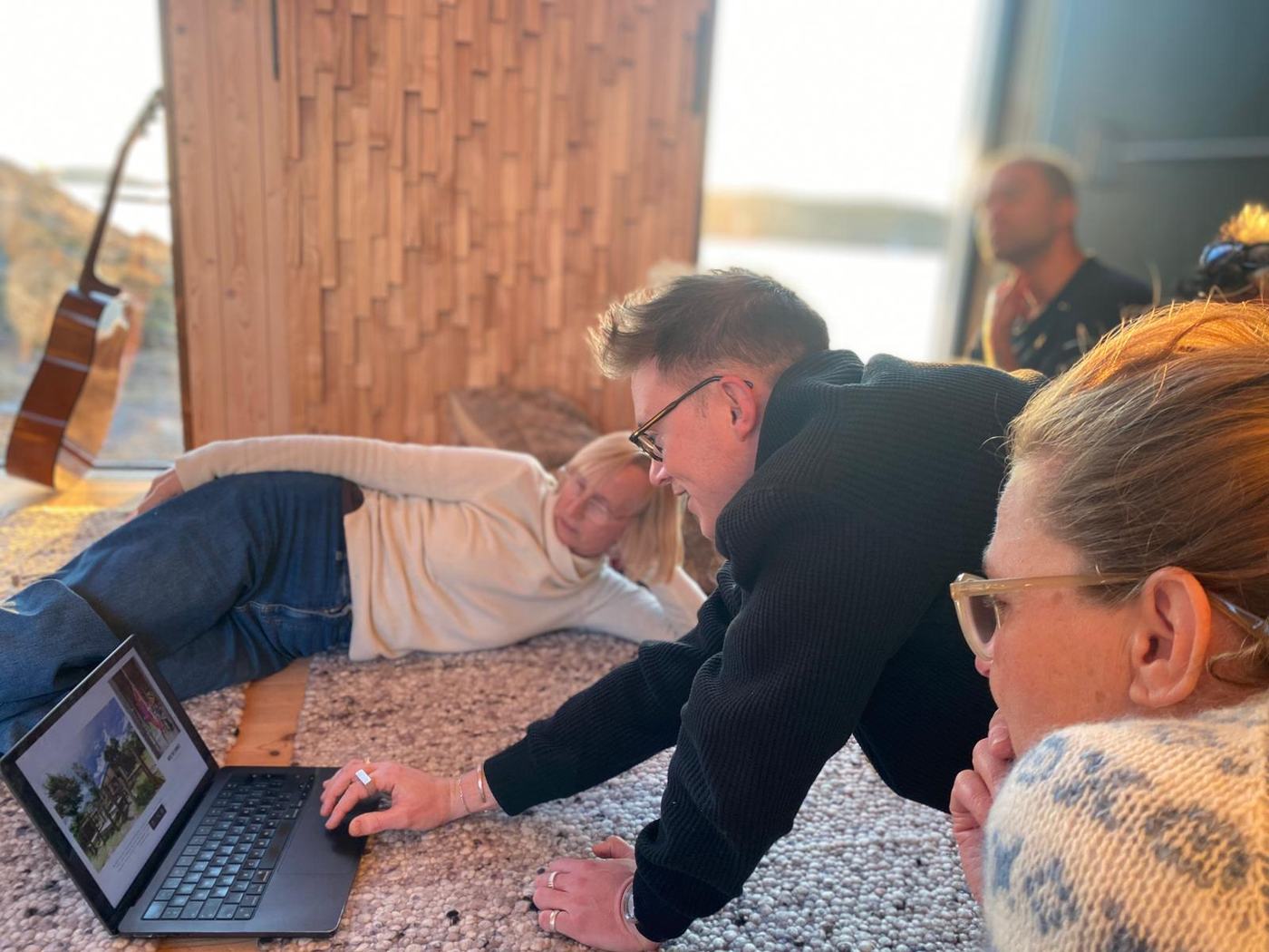Artists sharing work on a laptop, lying on the studio floor
