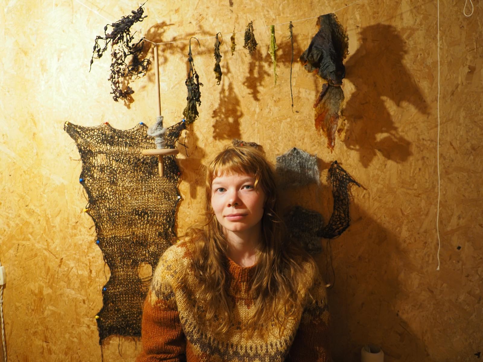 Victoria, a textile artist from Finland, in front of her work