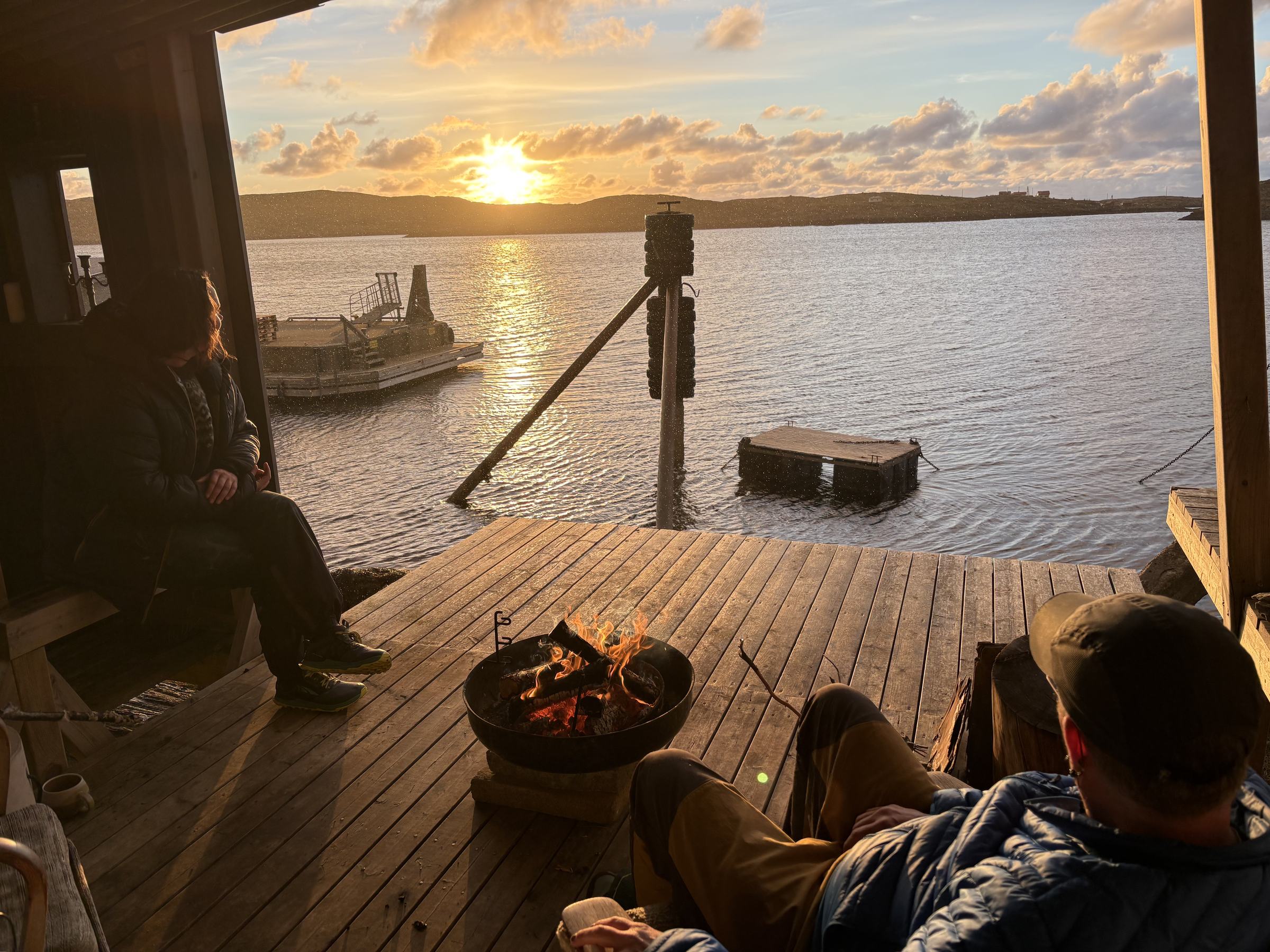 Guests around a fire on the Crab Shack deck at sunset