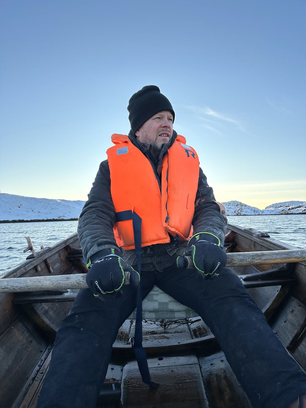 Håvard in a life jacket rowing a wooden boat